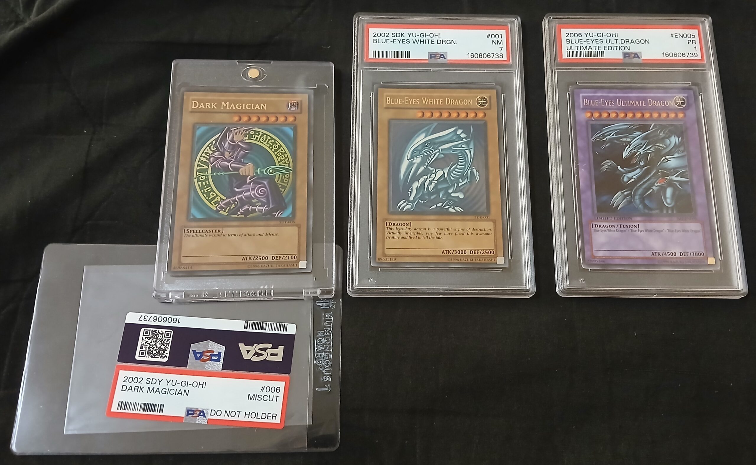 Dark Magician (SDY-006) - N8 MISCUT, Blue-Eyes White Dragon (SDK-001) - PSA NEAR MINT 7, Blue-Eyes Ultimate Dragon (JMP-EN005) - PSA POOR 1 (August 8, 2026)